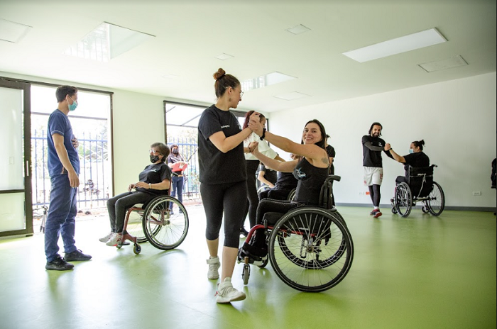 En la foto: Aura Lorena Varela, en silla de ruedas, bailando con una persona caminante.